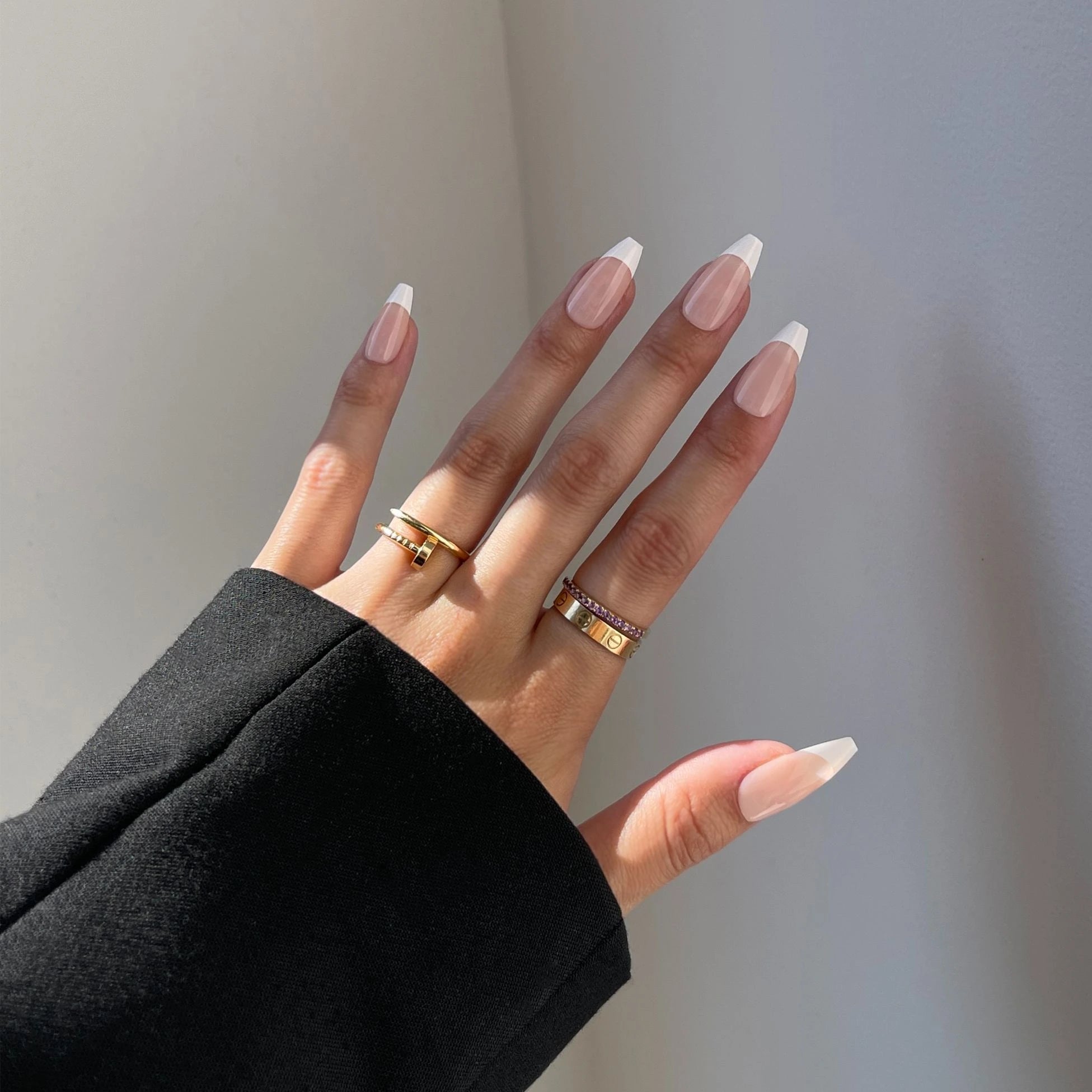 Business-polished hand wearing That Girl press-on nails, a classic French manicure in a long coffin shape for a sophisticated vibe.